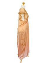A peach-colored satin nightgown or slip dress displayed on a wooden dress form mannequin.
