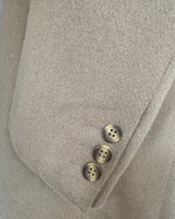 Close-up of a beige coat with three buttons on the sleeve.