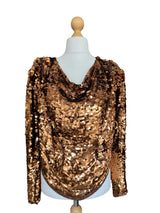 Gold sequin top on a mannequin against a neutral background