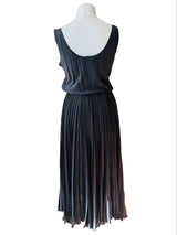 A black sleeveless dress displayed on a white mannequin, featuring a scoop neck top and a long pleated skirt.