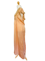 A peach-colored satin nightgown with gold lace trim displayed on a wooden dress form.