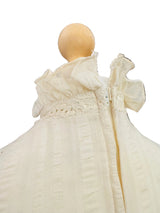 A cream-colored textured knit dress displayed on a mannequin, viewed from the back inside a boutique setting.