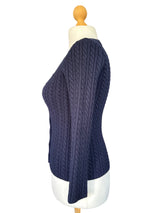 Blue textured sweater on a white mannequin stand .