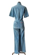 A light blue denim jumpsuit displayed on a mannequin from the back.